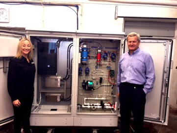 (Pictured: L-R, Nikki Wilson and Valeri Ilchenko in Tallinn, Estonia, with the N.O.W Impact Beverage Device, inside view of electrical and hydraulic cabinets).